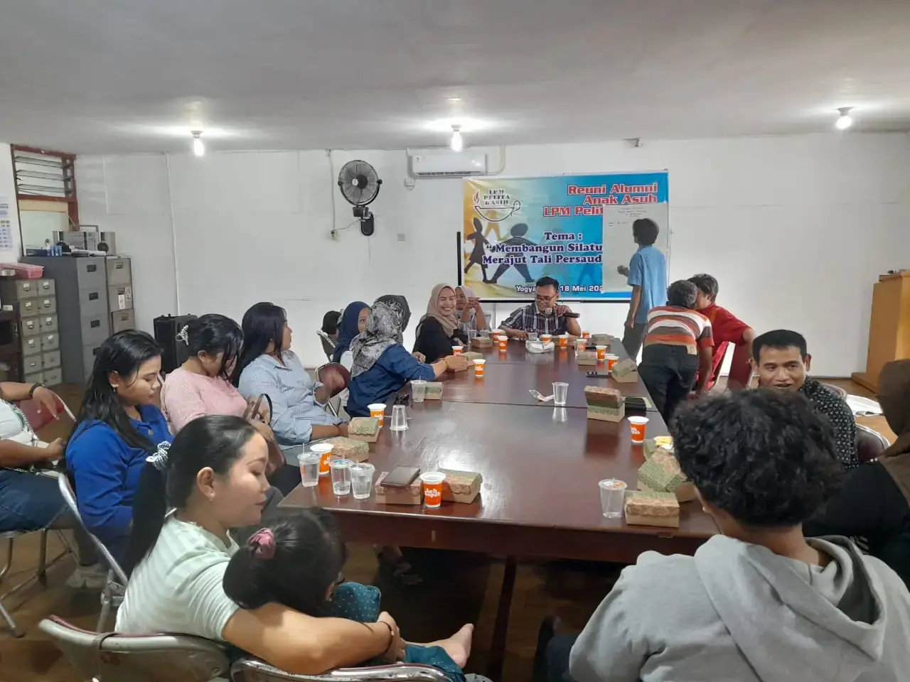 Alumni anak asuh duduk mengelilingi meja dalam reuni di aula LPM Pelita Kasih